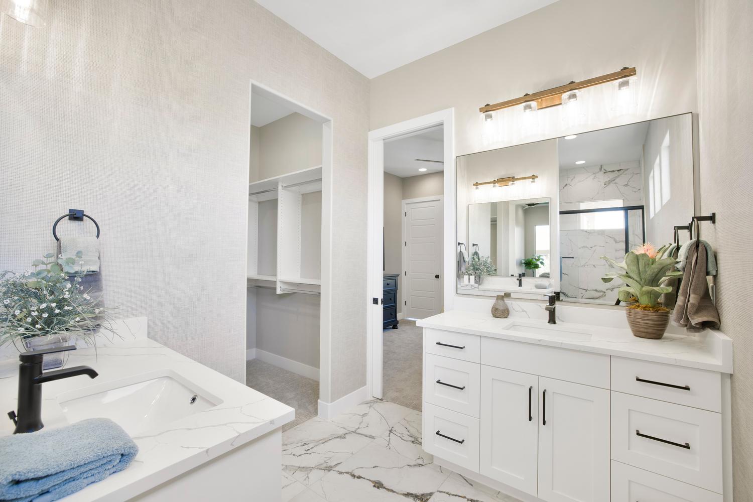 Bathroom with two vanities, light marble finish flooring, and a marble finish shower