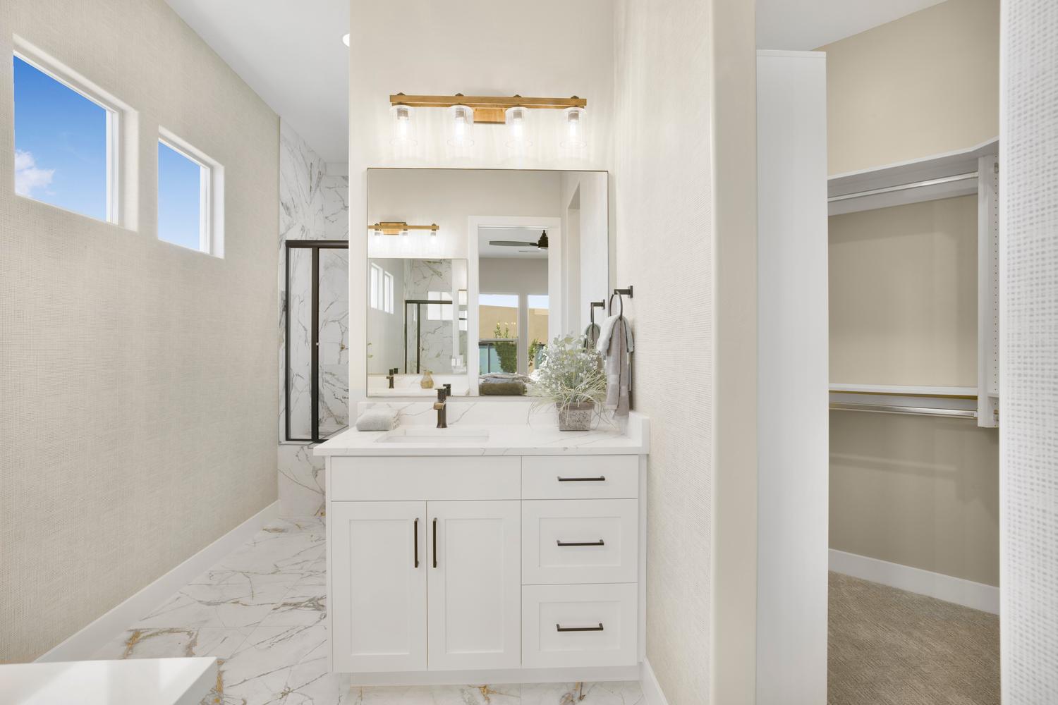 Bathroom featuring vanity, a walk in closet, a marble finish shower, and light marble finish floors