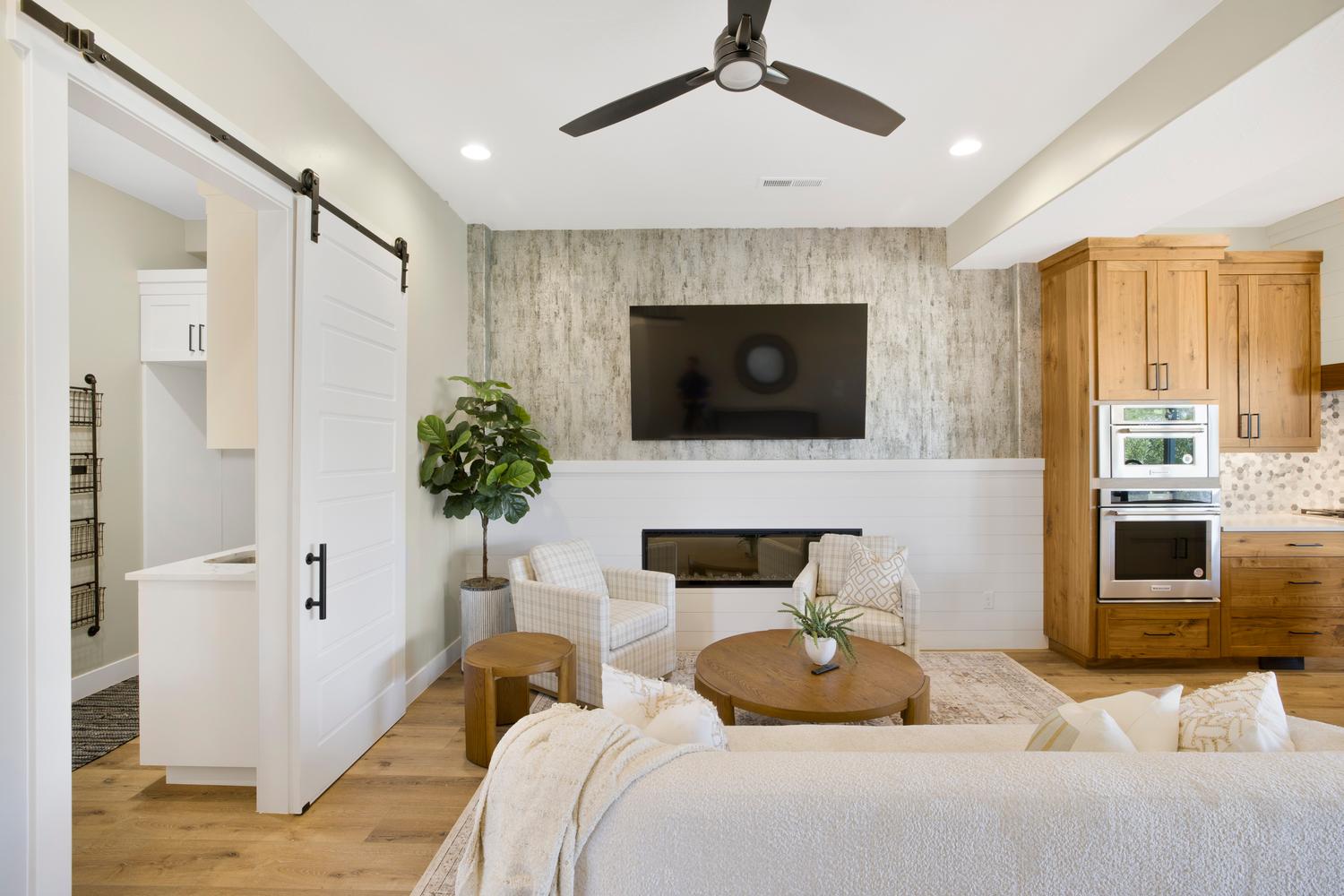 Living room with light wood finished floors, an accent wall, a barn door, a glass covered fireplace, and wallpapered walls