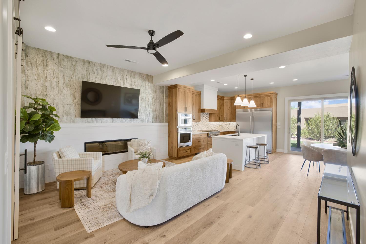 Living area with light wood finished floors, a glass covered fireplace, a ceiling fan, and recessed lighting