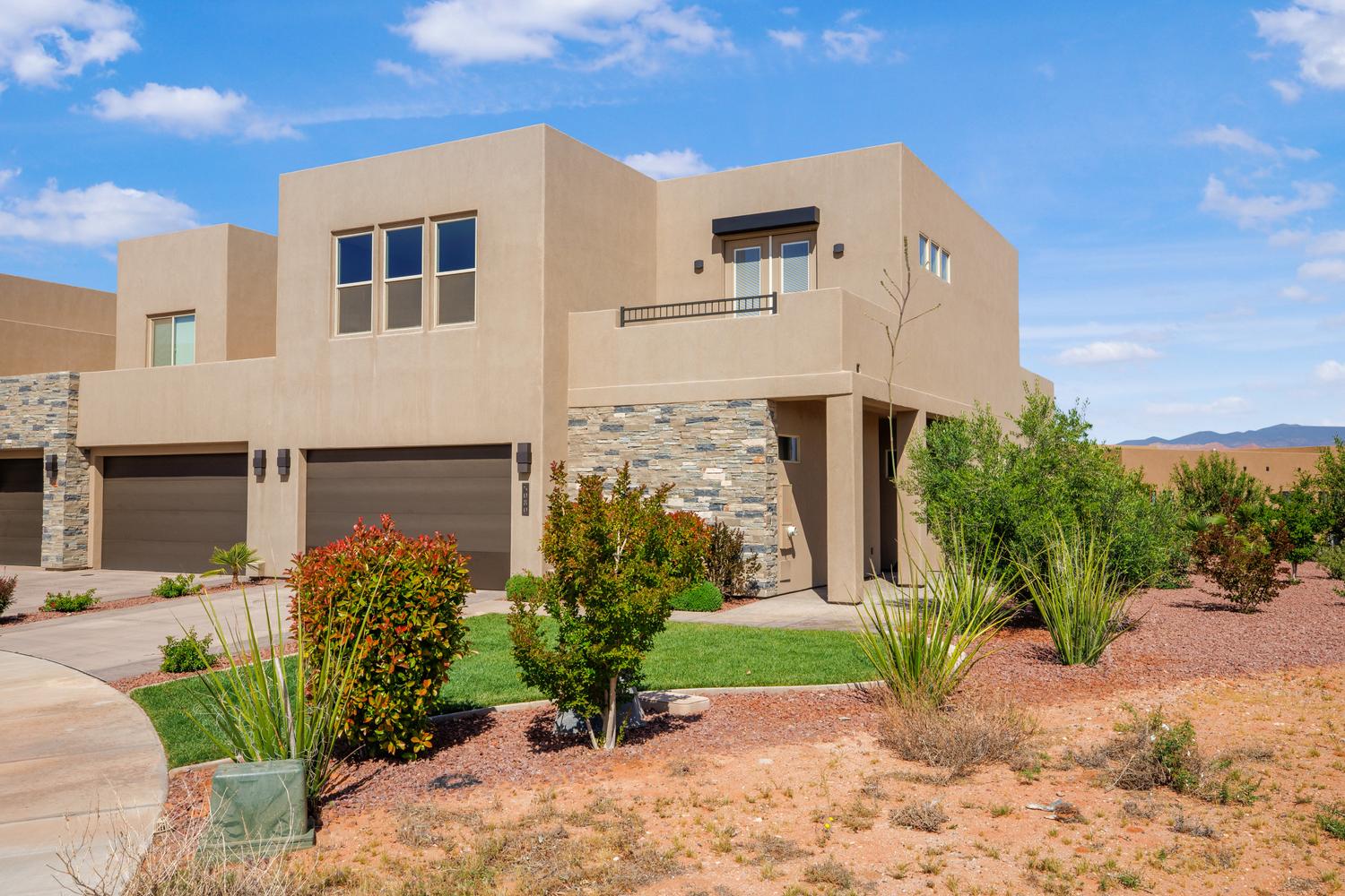 View of front of home featuring an attached garage, stucco siding, driveway, and stone siding