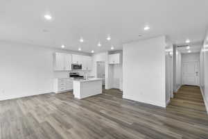 Kitchen featuring white cabinets, an island with sink, light wood-type flooring, recessed lighting, and stainless steel appliances
