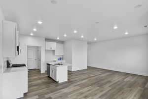 Kitchen with white cabinetry, recessed lighting, a center island with sink, dark wood finished floors, and open floor plan