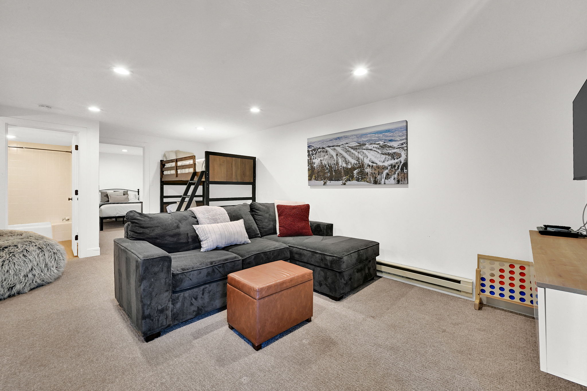 Downstairs living room with carpet, flexible occupancy space, full bathroom, nook for various functions.