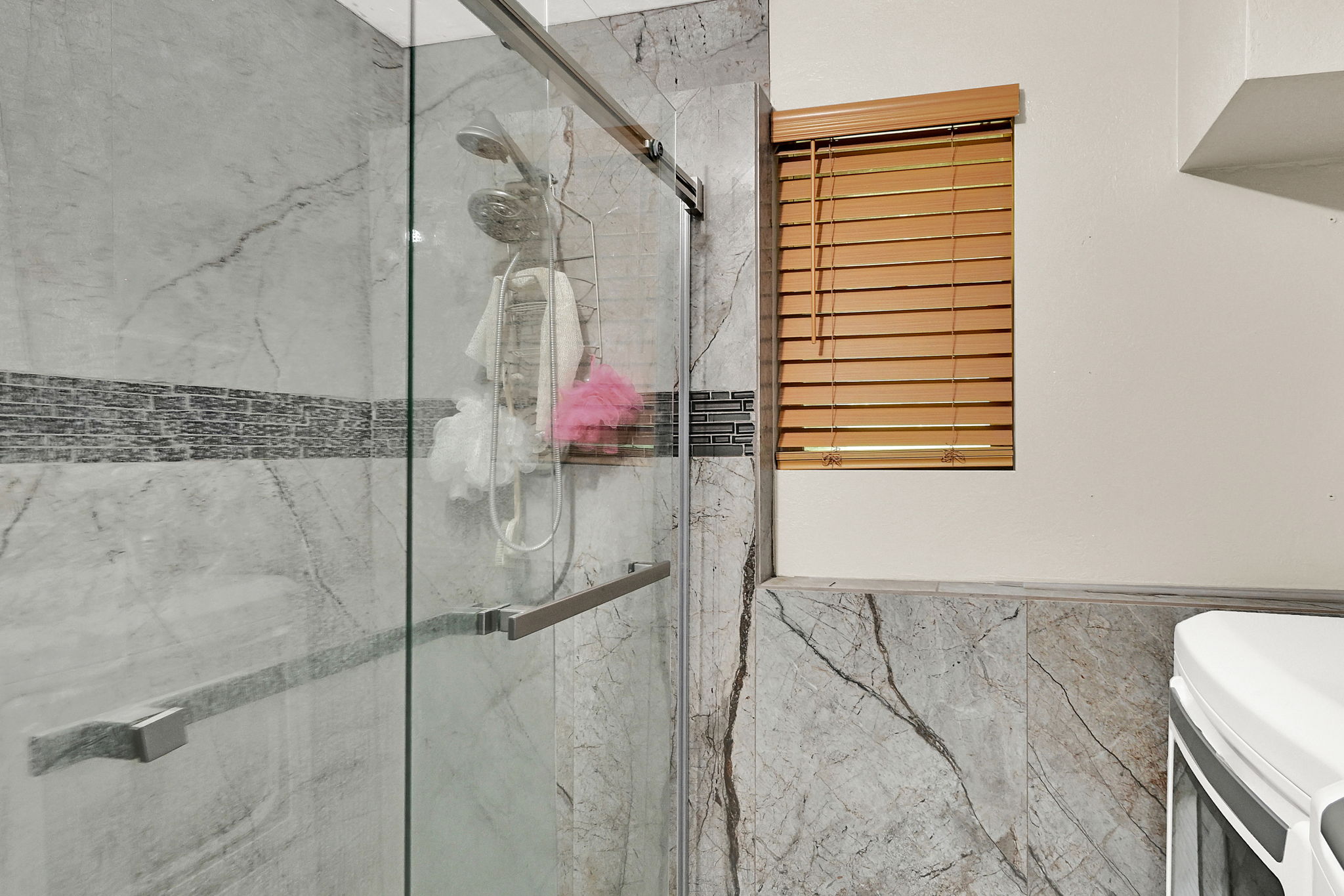 Full bath with a marble finish shower and wainscoting