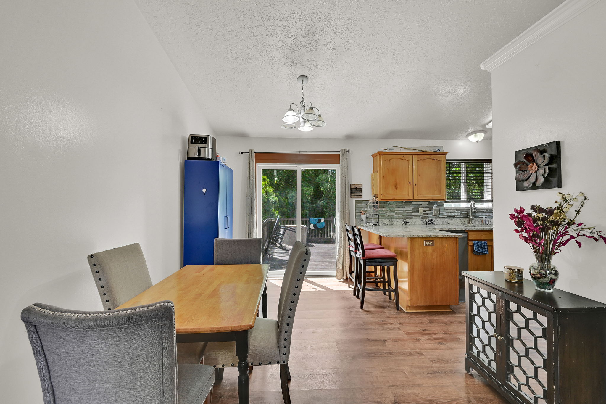 Dining room with light wood-type flooring, a textured ceiling, and suspended lighting