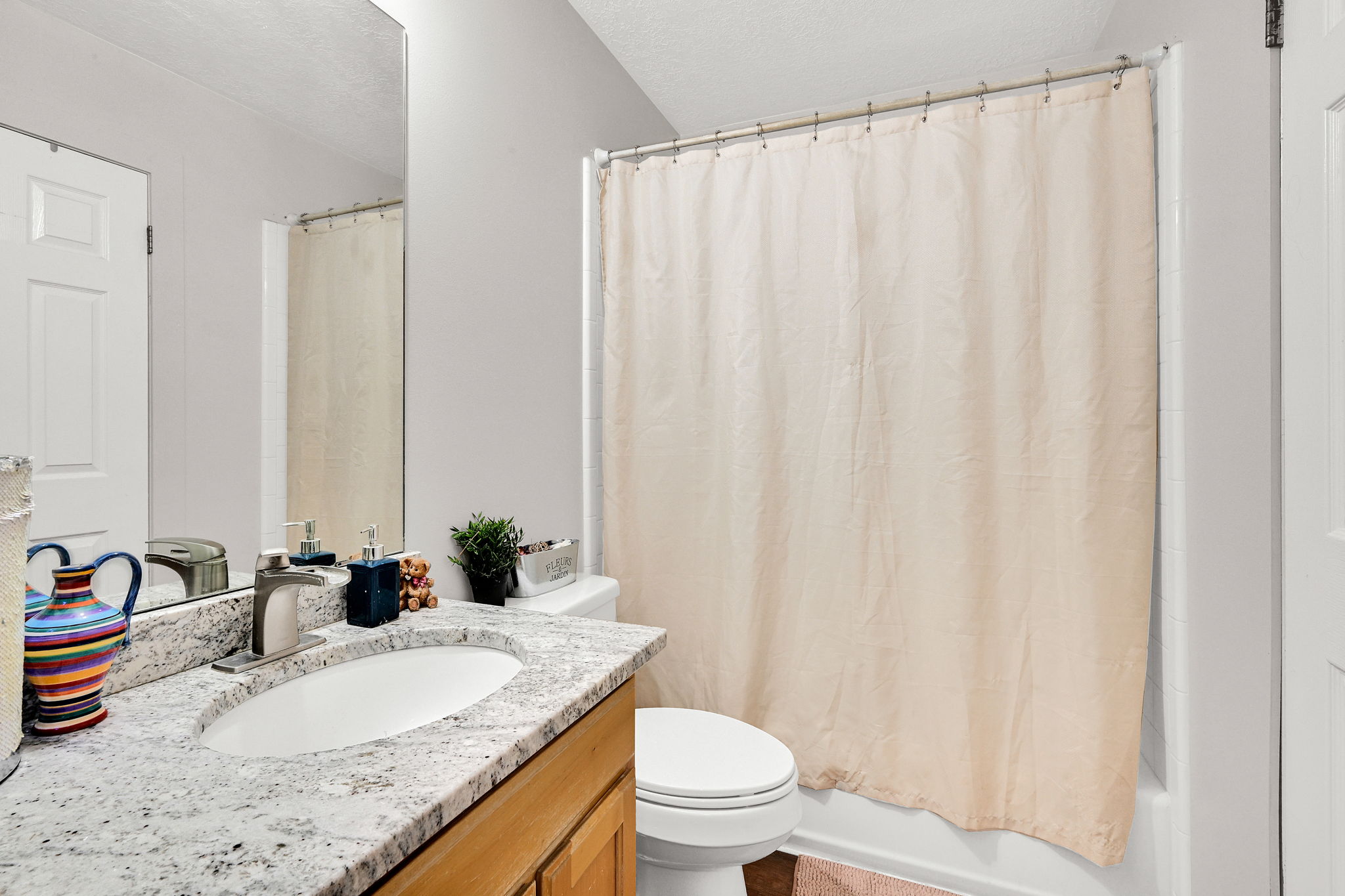 Full bath with vanity, a textured ceiling, and shower / tub combo with curtain