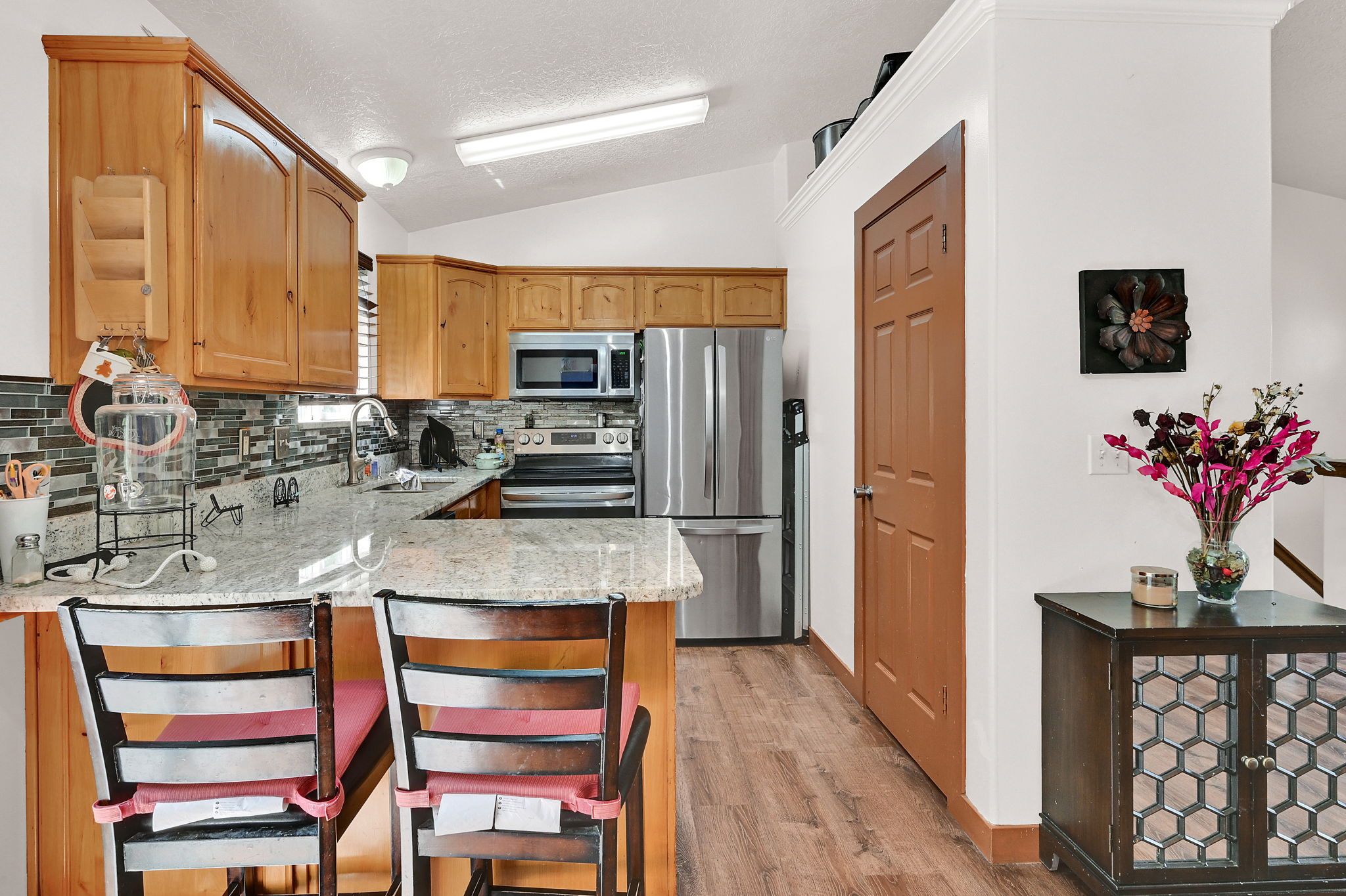 Kitchen featuring light stone countertops, stainless steel appliances, a peninsula, tasteful backsplash, and a kitchen breakfast bar