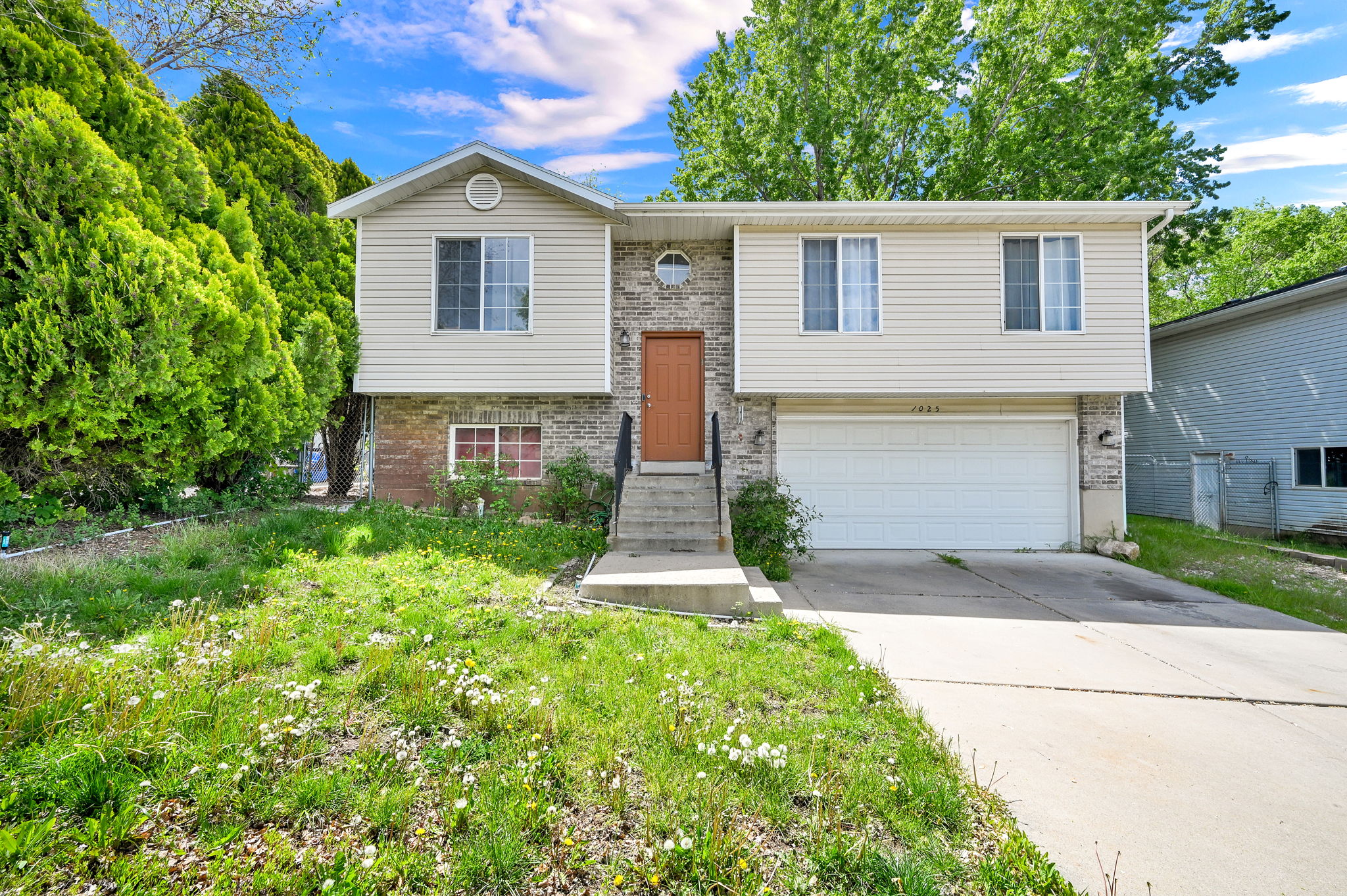 Split foyer home featuring concrete driveway, brick siding, and a garage
