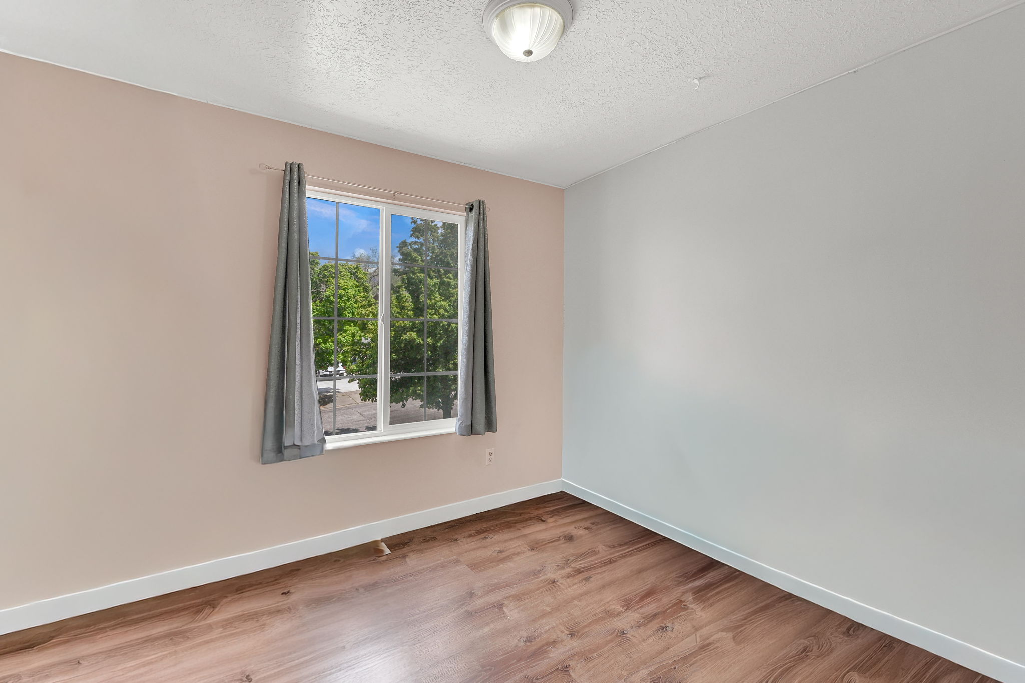 Empty room with light wood-style floors and a textured ceiling