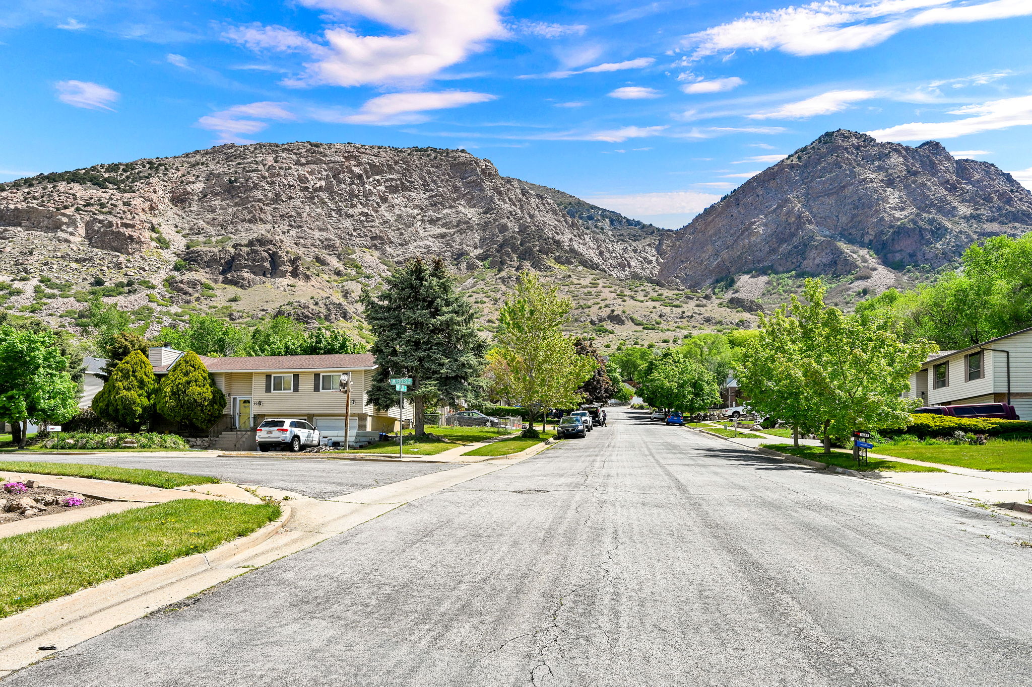 View of asphalt street featuring a mountain view, sidewalks, curbs, and a residential view