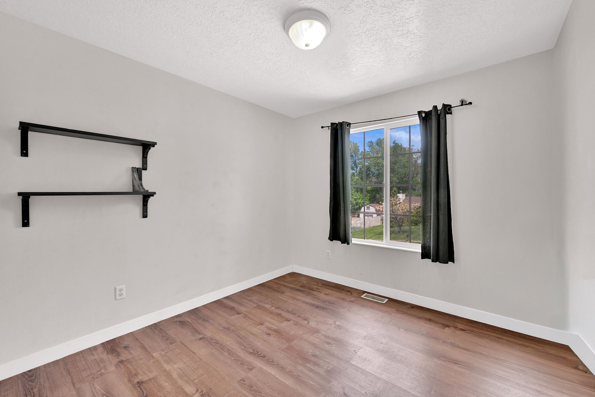 Unfurnished room featuring light wood-style floors and a textured ceiling