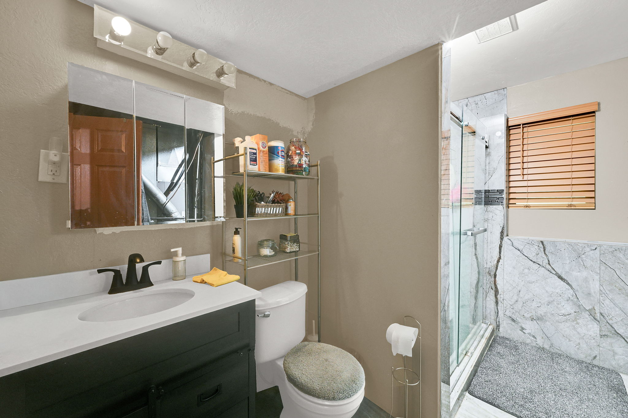 Bathroom with vanity and a marble finish shower