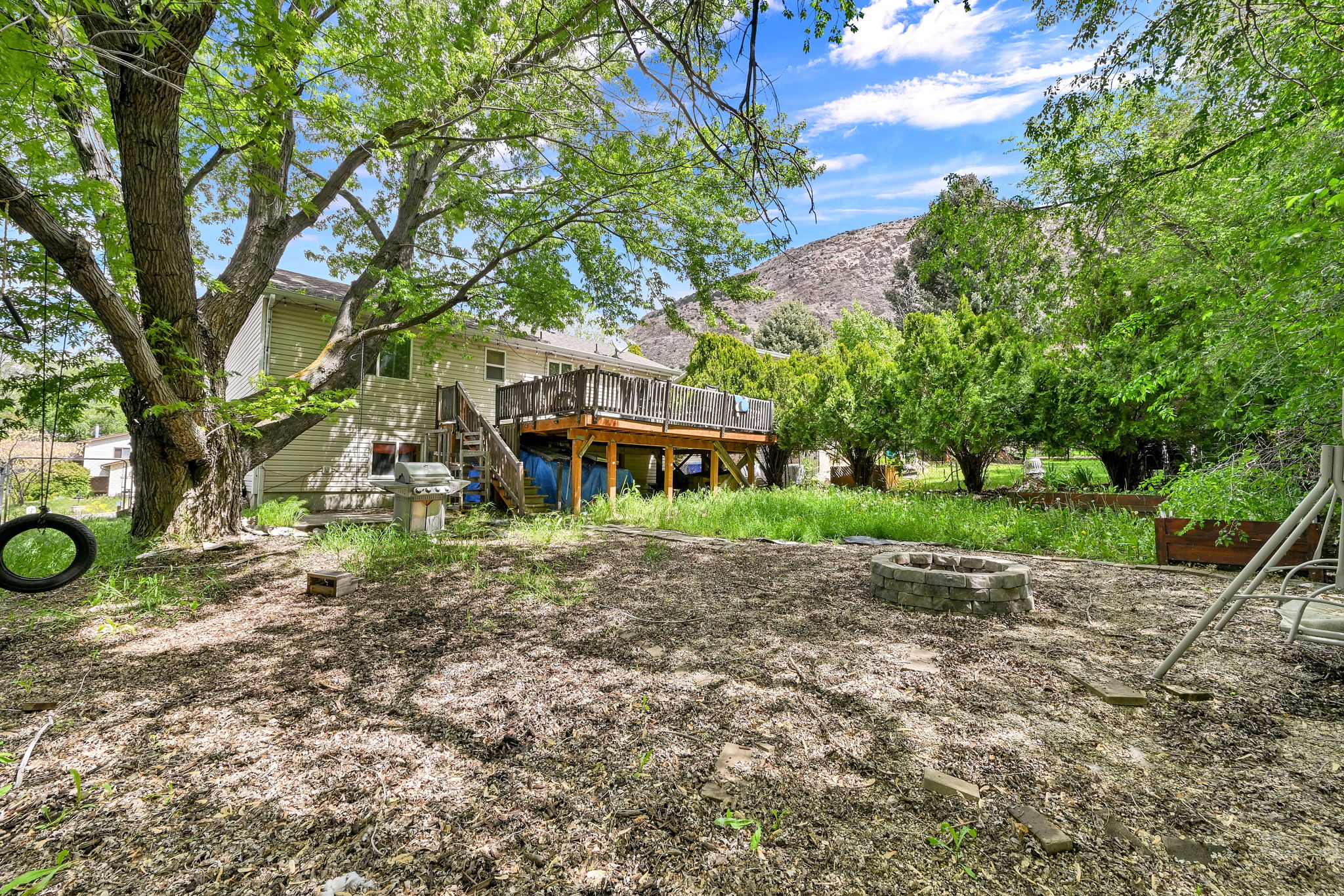Back of house with a deck with mountain view and a fire pit