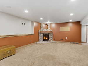 Spacious interior featuring a corner stone-clad fireplace with a rustic wood mantel, carpeted flooring, recessed lighting, and a two-tone wall treatment