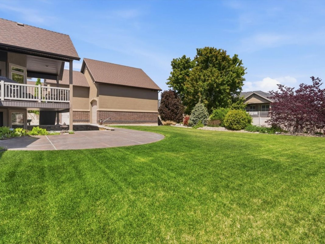 Expansive green lawn with a large, curved concrete patio