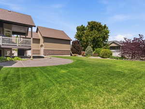 Expansive green lawn with a large, curved concrete patio