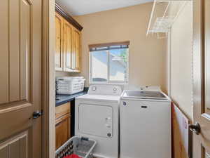 Laundry area featuring wood cabinetry, dark countertop, and a window with blinds
