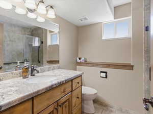 Bathroom featuring a light-toned vanity with an integrated sink and a speckled countertop