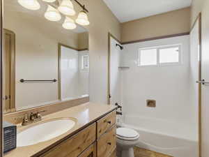 Bathroom featuring a light-toned vanity with an integrated sink, a rectangular mirror, and a wall-mounted light fixture