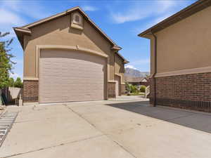 Stucco exterior with brick detailing, featuring a two-car garage with a panel door, and a concrete driveway