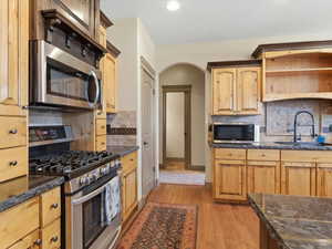 Kitchen featuring wood cabinetry, dark countertops, and stainless steel appliances including a gas range and built-in microwave
