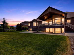 Rear exterior with a spacious lawn, covered patio, and ground-level patio access