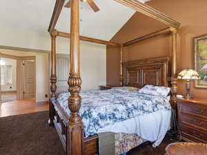Vaulted ceiling with a ceiling fan, brown wall accent, wood-finish flooring, and arched doorways