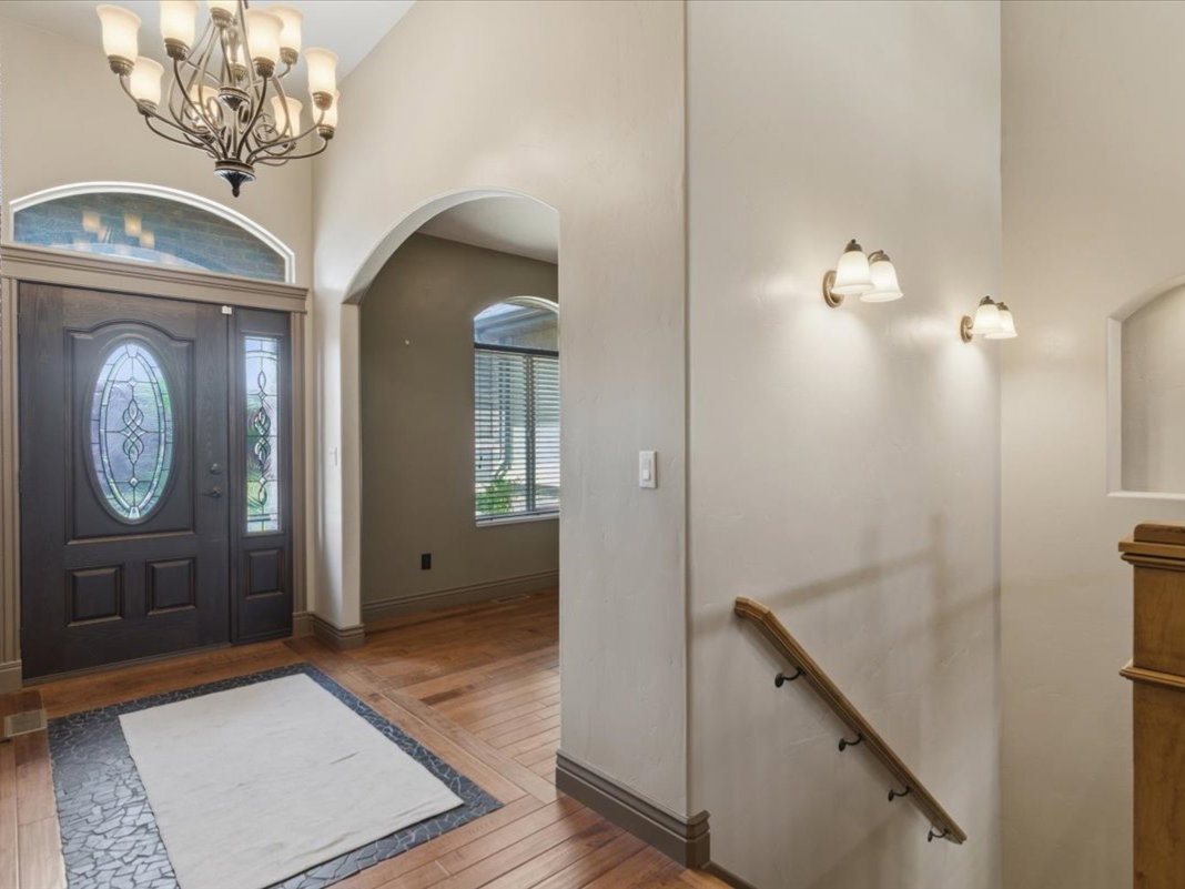 Grand entry foyer featuring a dark wood door with oval leaded glass, a sidelight, and an arched transom window