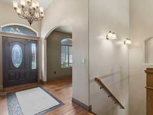 Grand entry foyer featuring a dark wood door with oval leaded glass, a sidelight, and an arched transom window