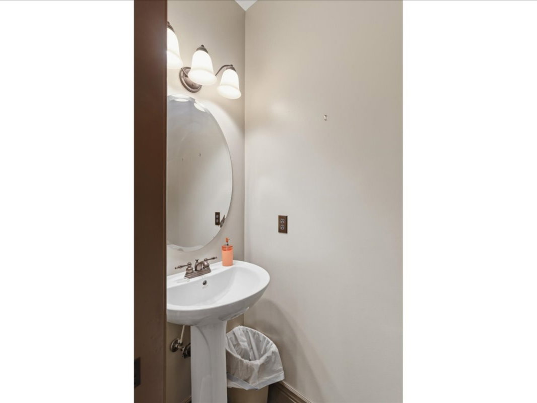 Pedestal sink with chrome-finish faucet and oval mirror