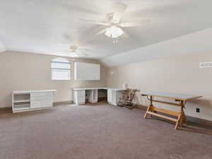 Spacious room featuring carpeting, two ceiling fans, built-in white cabinetry, a built-in white desk with drawers, and an arched window
