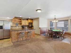 Entertainment area featuring a wood-finish bar with a dark countertop, stainless steel refrigerator, and wood-finish cabinetry