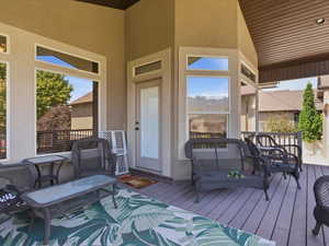 Covered outdoor deck featuring composite decking, recessed lighting, expansive windows, and a glass-paneled door