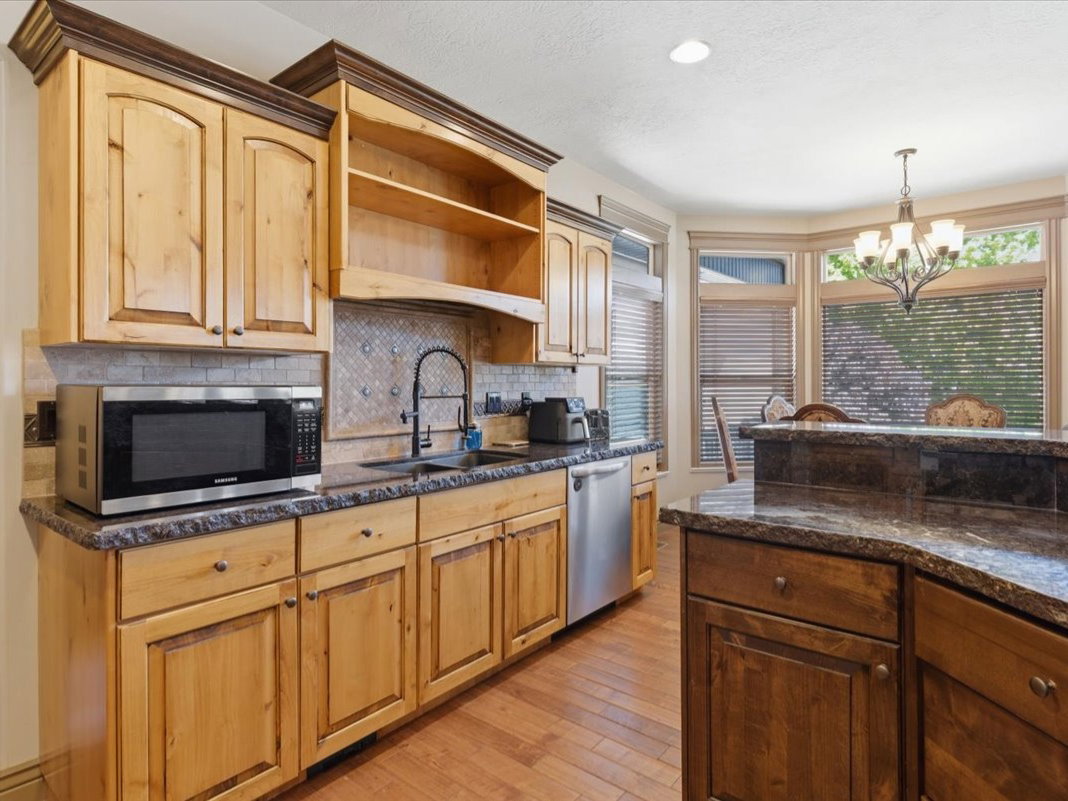 Kitchen featuring natural wood cabinetry, stone countertops, a mosaic tile backsplash, and stainless steel appliances