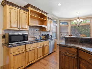 Kitchen featuring natural wood cabinetry, stone countertops, a mosaic tile backsplash, and stainless steel appliances