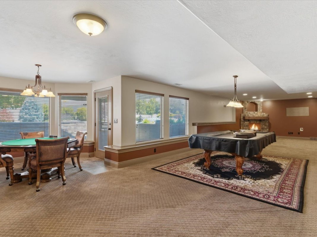 Spacious lower-level entertainment area featuring a stone fireplace, recessed lighting, and multiple windows