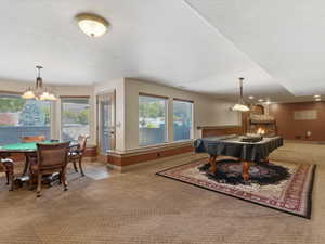 Spacious lower-level entertainment area featuring a stone fireplace, recessed lighting, and multiple windows