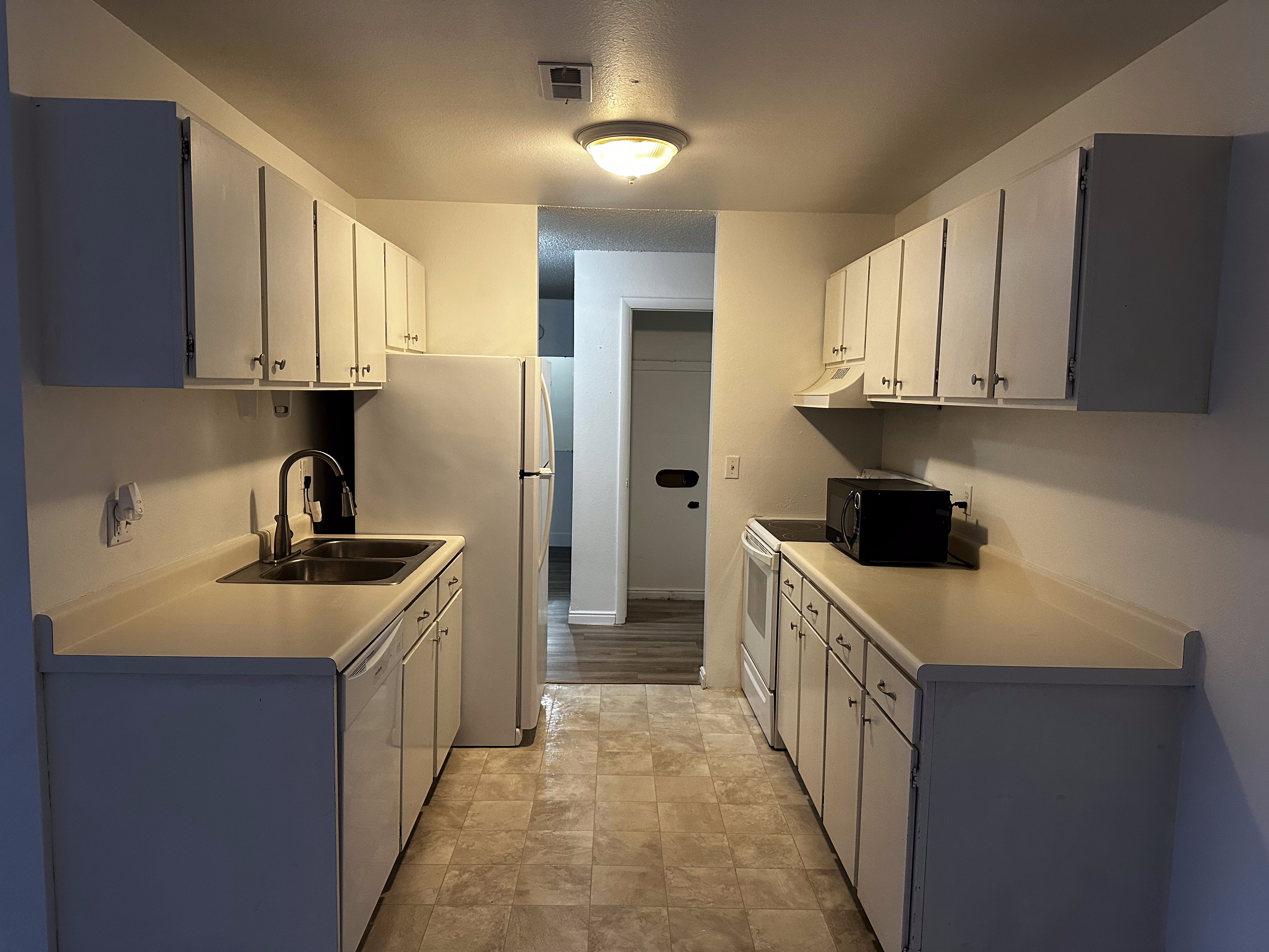 Bright, clean kitchen with white cabinetry, light countertops, and all appliances included. Functional layout with great storage.