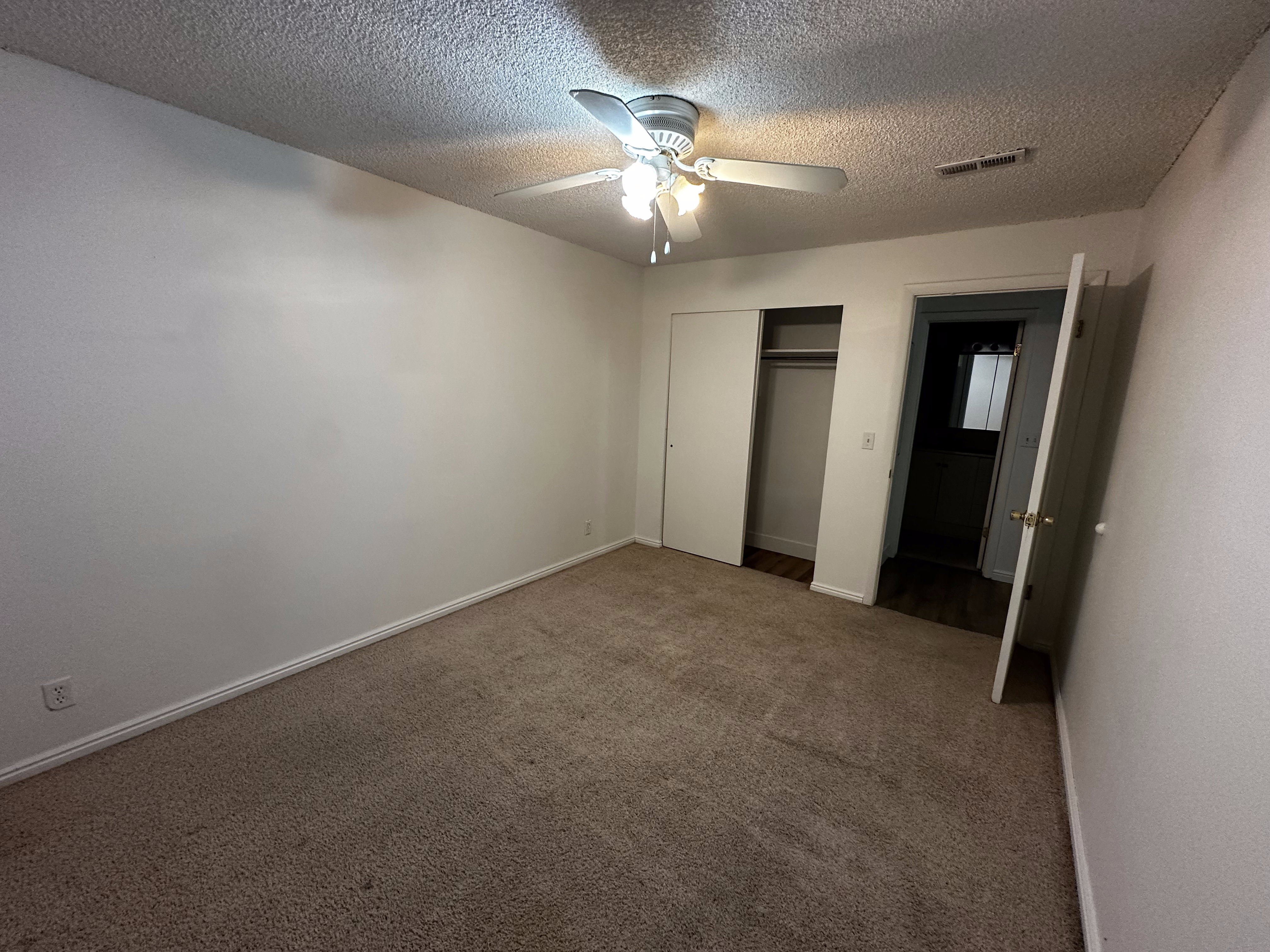 Spacious primary bedroom with closet, ceiling fan, and clean, neutral finishes.