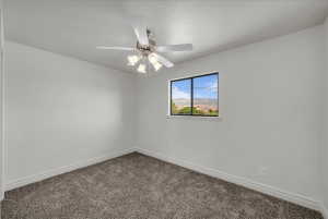 Unfurnished room with dark colored carpet and ceiling fan