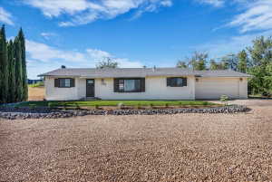 Ranch-style house with driveway, a garage, roof with shingles, and a front lawn