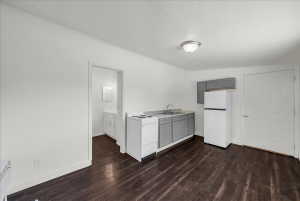 Kitchen with light countertops, white appliances, gray cabinets, dark wood-style flooring, and a textured ceiling