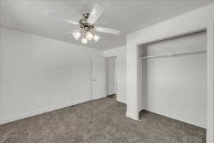 Unfurnished bedroom featuring dark colored carpet, a closet, and ceiling fan