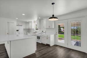 Kitchen featuring white appliances, white cabinetry, ornamental molding, a center island, and dark wood-style floors