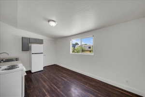 Kitchen with gray cabinets, light countertops, white appliances, and dark wood-style floors