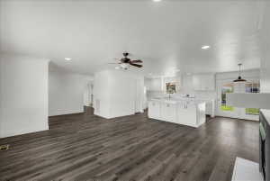 Unfurnished living room featuring recessed lighting, ceiling fan, dark wood finished floors, and crown molding