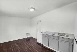 Kitchen with gray cabinetry, light countertops, white electric range oven, dark wood-type flooring, and stainless steel fridge