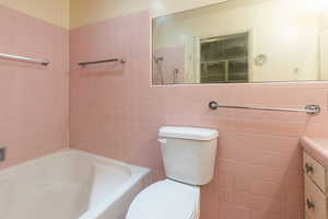 Full bath with vanity, tile walls, and shower / tub combination