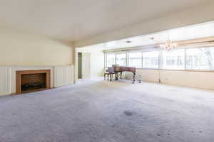 Carpeted living area with hanging lights and a fireplace